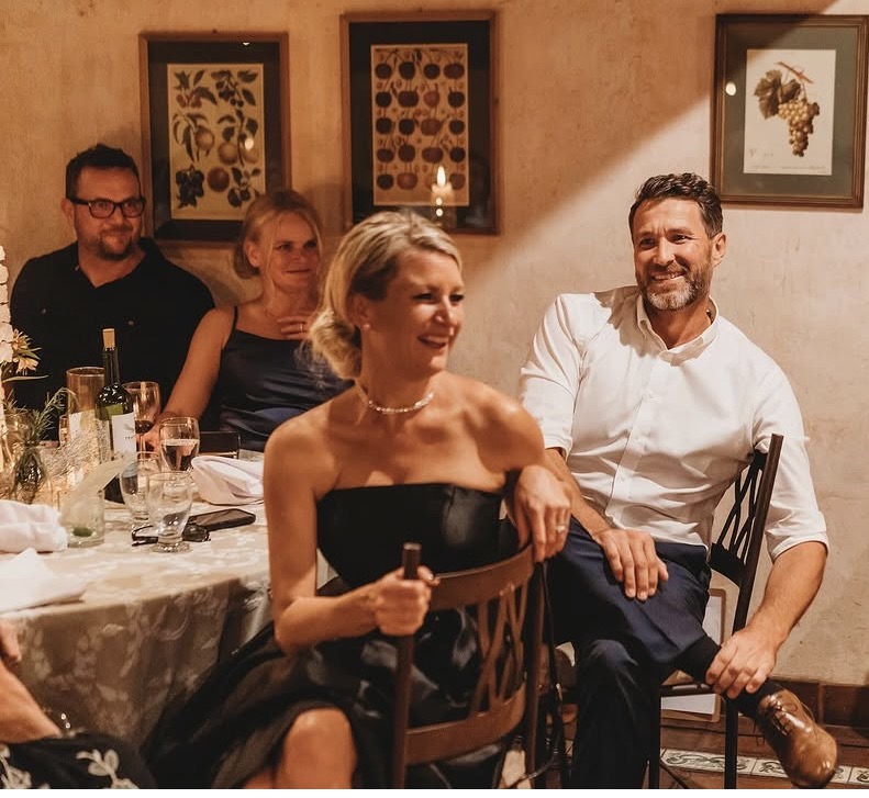 Pam and Sheldon at a dinner table with friends.