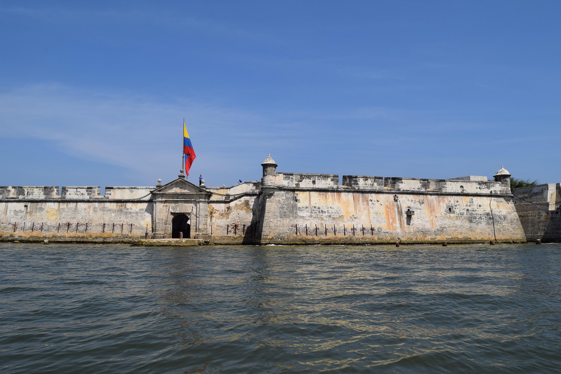 The stone walls of Cartagena's historic fortifications rising from the Caribbean Sea, Colombian flag flying above