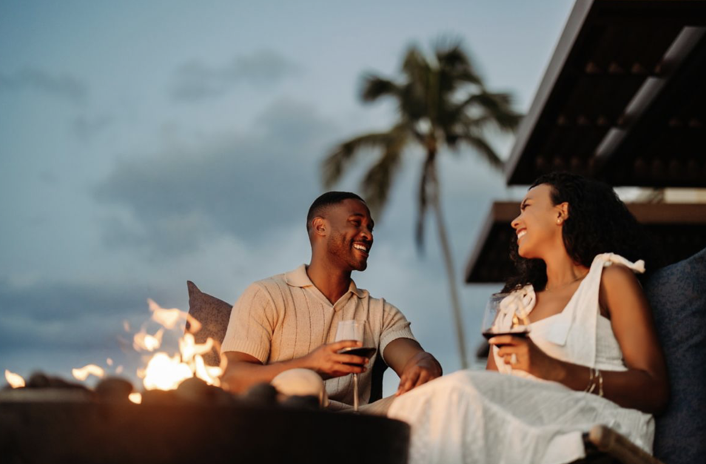 Couple relaxing by a fire pit at a Hawaii resort at dusk