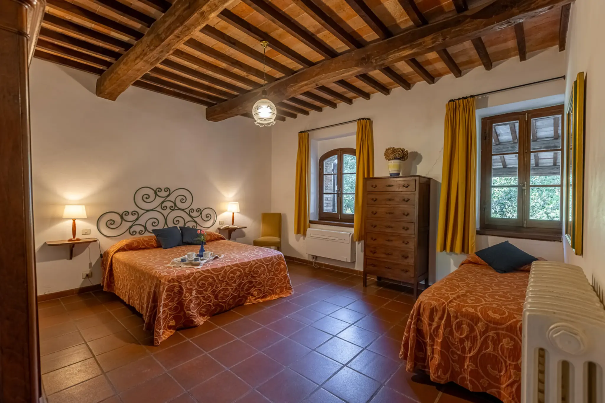 Bedroom with terracotta floors and white linens at Villa Serenzia, Tuscany