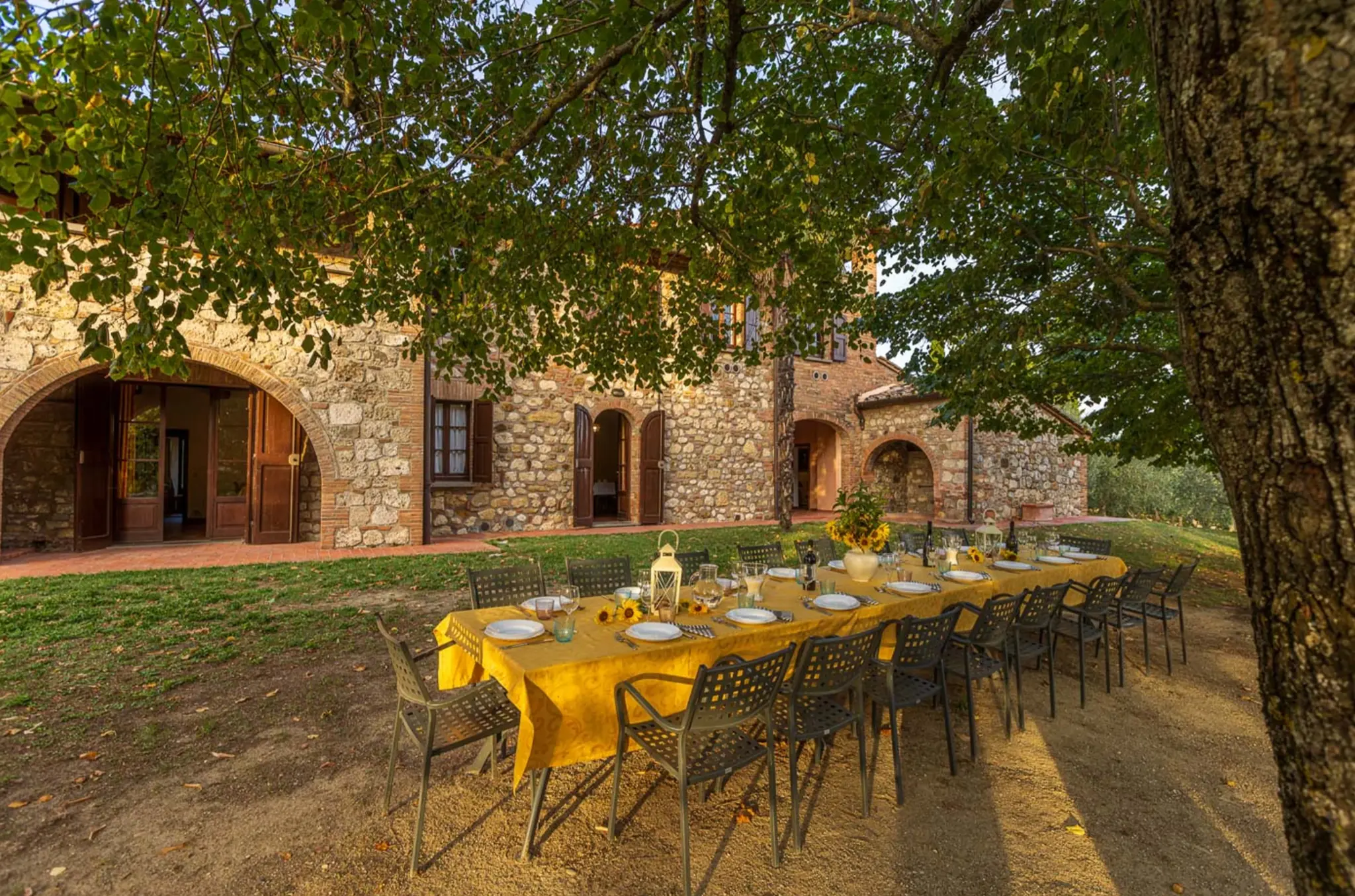 Outdoor dining table set under a pergola at Villa Serenzia, Tuscany, with terracotta pots and cypress trees